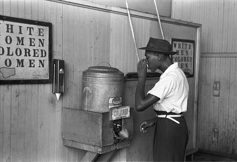 A man drinking from a segregated 'Colored' water fountain